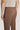 Brown plain front trousers with flat waistband and back button closure on male model.