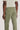 Person wearing olive-green chino pants with a cream-colored t-shirt, shown from behind at waist level.