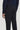 Man wearing navy sweater and black solid stretch trousers with button closure and side pockets.