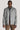 Man wearing grey herringbone shirt jacket with button front and collar over navy shirt and brown corduroy pants.