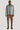 Man wearing grey herringbone shirt jacket with button front and pointed collar over navy shirt, paired with brown corduroy tr