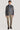Man wearing grey herringbone shirt jacket over blue shirt, paired with beige trousers and black shoes.