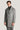 Man wearing gray and white herringbone topcoat with notch lapels over dark turtleneck.