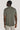 Sage-colored crew neck t-shirt with short sleeves, shown from the back on a model wearing light-colored pants.