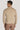 Sand-colored long sleeve polo with houndstooth pattern on shoulders, worn with brown trousers, shown from back.