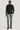 Black long sleeve button-down sweater with collar worn with gray trousers.