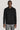 Black long sleeve button-down sweater with knit collar and white buttons worn with gray pants.