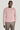 Pink crewneck sweatshirt with ribbed knit texture worn with gray trousers.