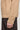 Beige knit crewneck sweater with cable pattern on left side and ribbed cuffs, worn with dark pants.