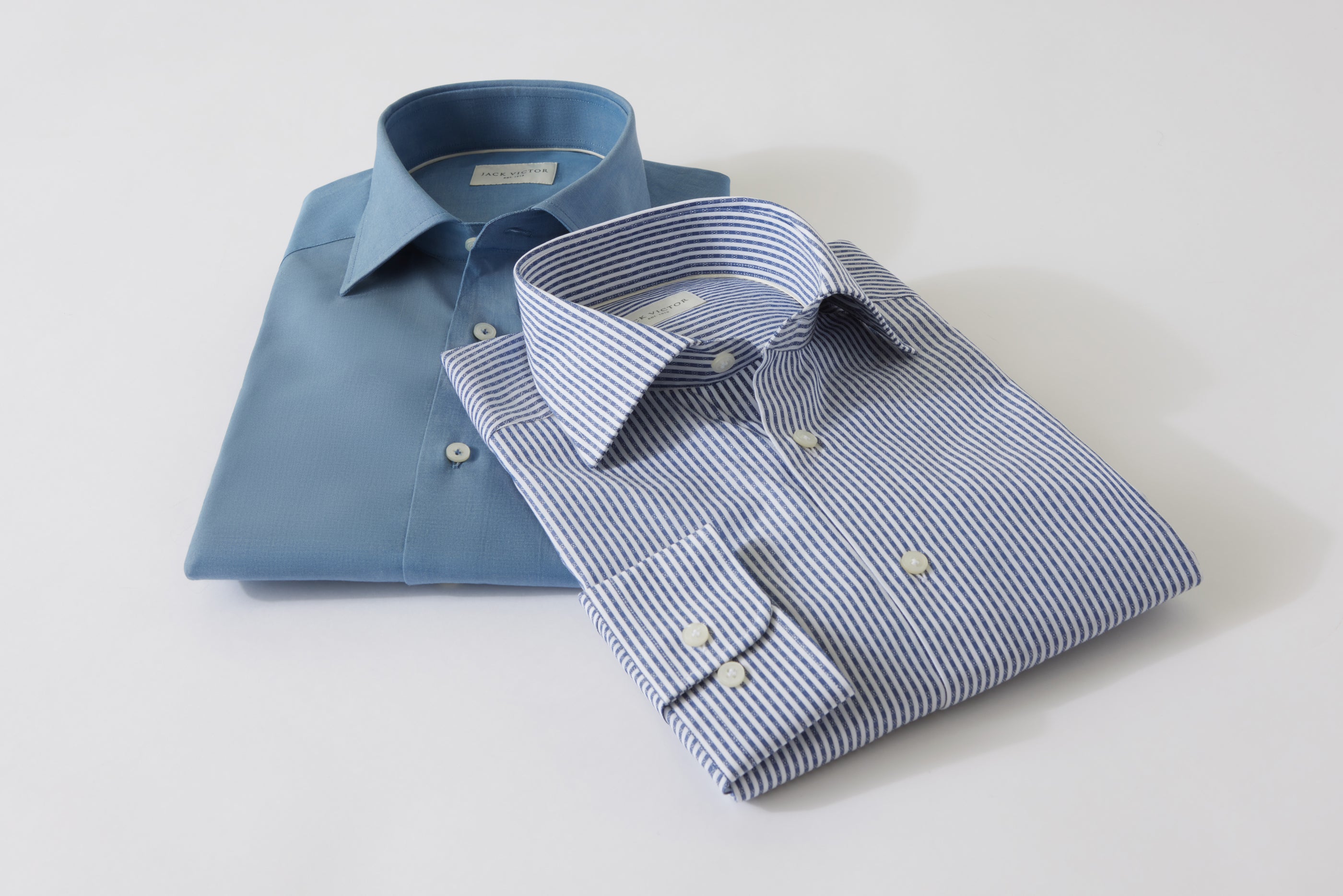 two different Jack victor colored folded sport shirts laying flat