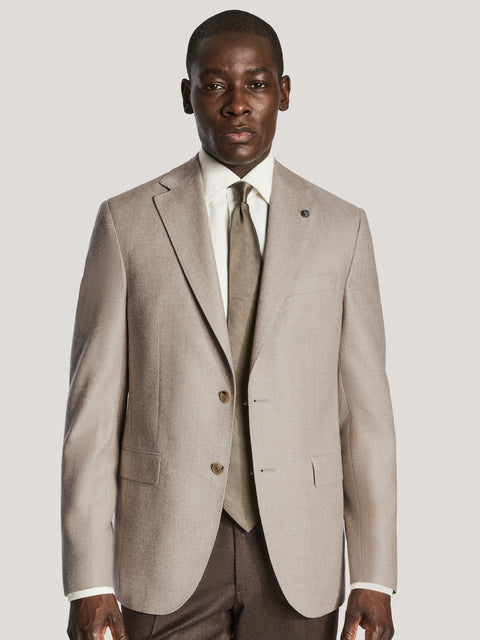 Beige single-breasted blazer with notch lapels, button front, and patch pockets worn with white dress shirt and knit tie.