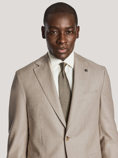 Beige blazer with notch lapels, button front, and chest pocket, worn with white dress shirt and olive tie.