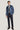 Man wearing mid blue plain blazer with notch lapels and single chest pocket over gray turtleneck and black trousers.