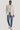 Man wearing cream solid blazer with notch lapels over a cream shirt, paired with blue jeans and white sneakers.